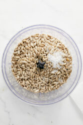 Transferring sunflower seeds and salt to a food processor.