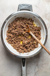 Browning ground beef and onions in a skillet for cheeseburger fries.