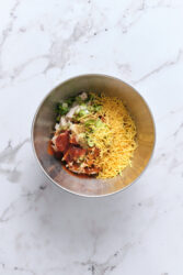 Mixing shredded chicken, refried beans, salsa, cheese, green onions, and spices in a bowl for chimichangas.