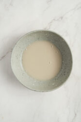 Warm water, yeast, and sugar mixture for pork buns proofing in a bowl.