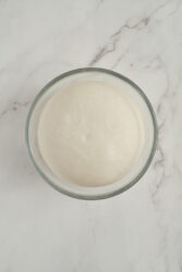 Risen dough for pork buns in a glass bowl.