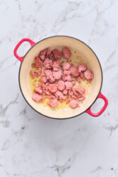 Browning Italian sausage in a red pot for sausage and lentil soup.