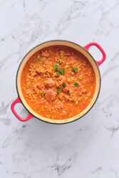 Sausage and lentil soup in a red Dutch oven.