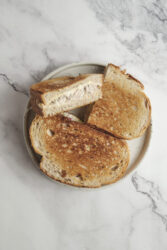 A toasted tuna melt sandwich, cut in half, on a plate.