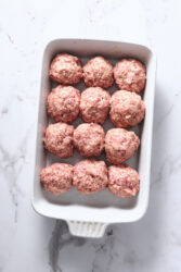 Formed ham balls placed in a white baking dish.