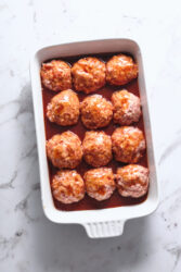 Ham balls in a white baking dish with sweet glaze.