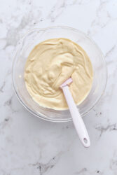 Mixing peanut butter cheesecake filling in a glass bowl.