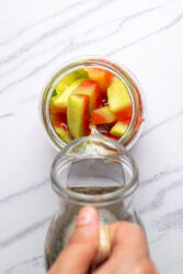 Pouring liquid over watermelon rind pieces in a jar for pickles.